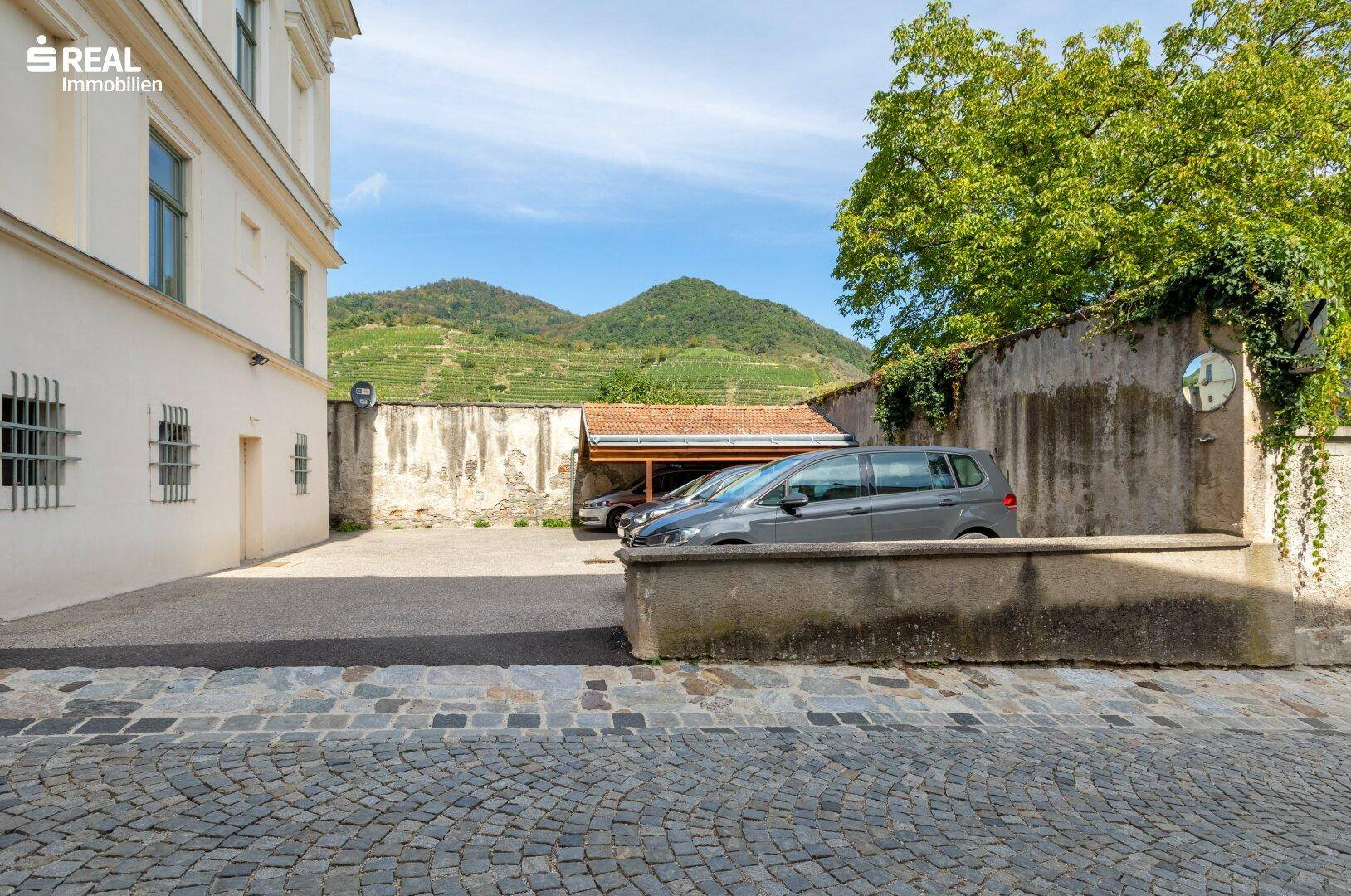 Außenansicht eines Parkplatzes mit einem Auto und einem malerischen Blick auf die Weinberge.