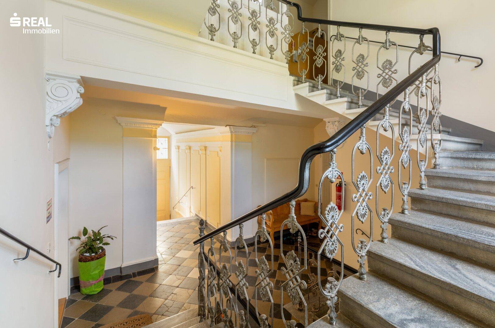 Weitläufiges Treppenhaus mit elegantem Geländer, Stuckelementen und natürlichem Lichteinfall.