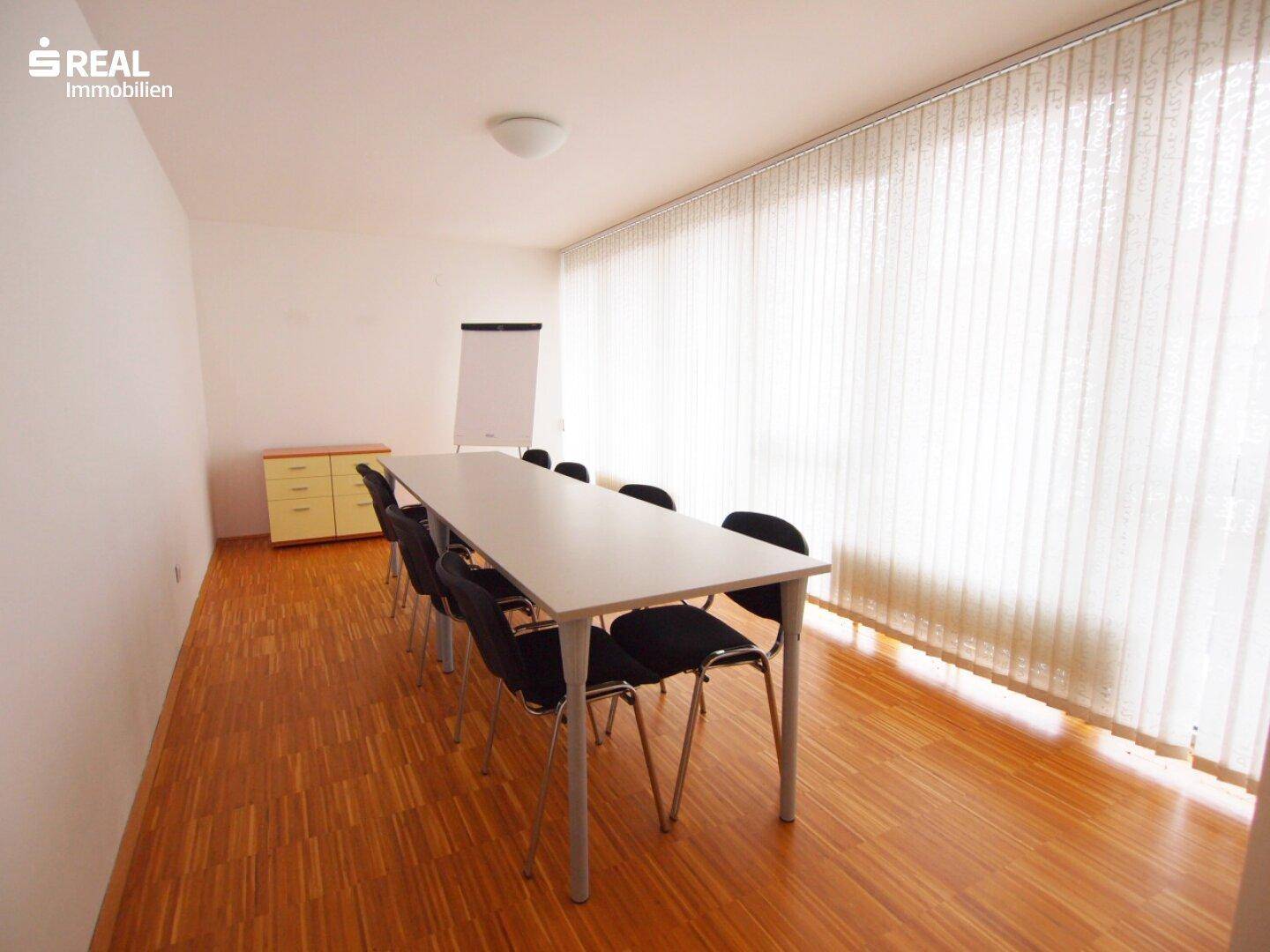 Großer Ess- oder Konferenzraum mit langem Tisch, vielen Stühlen und breiten Fenstern.
