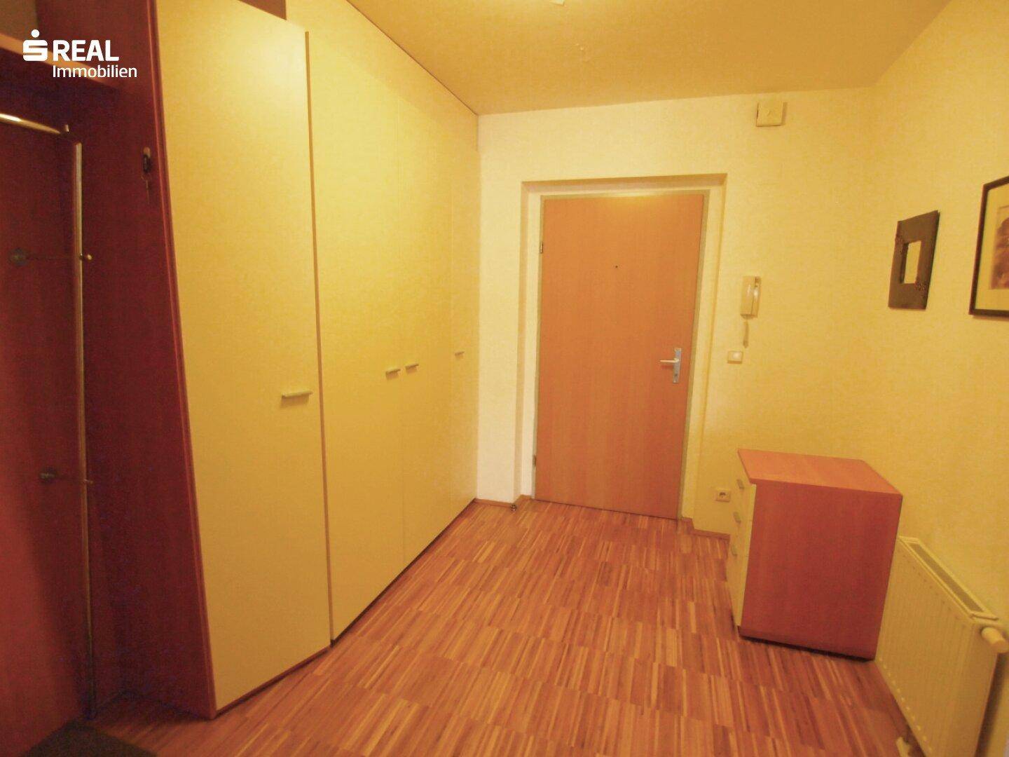 Heller Flur mit praktischen Einbauschränken und Holzboden, der zu weiteren Räumen führt.