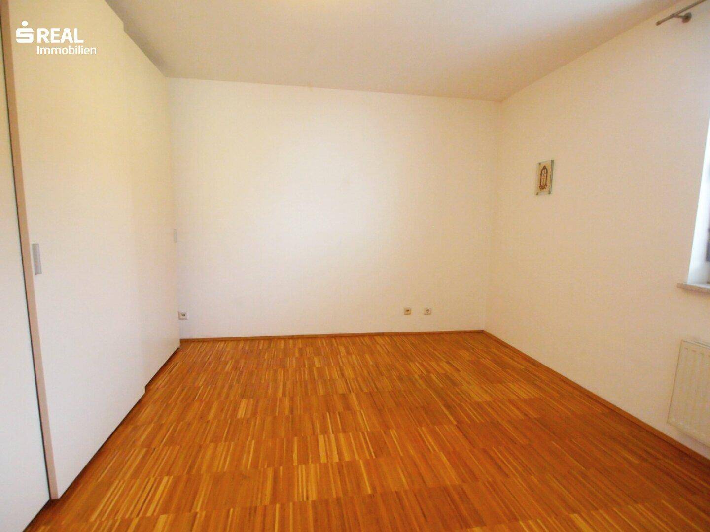 Geräumiges Schlafzimmer mit Holzboden und einem praktischen Einbauschrank an der Wand.