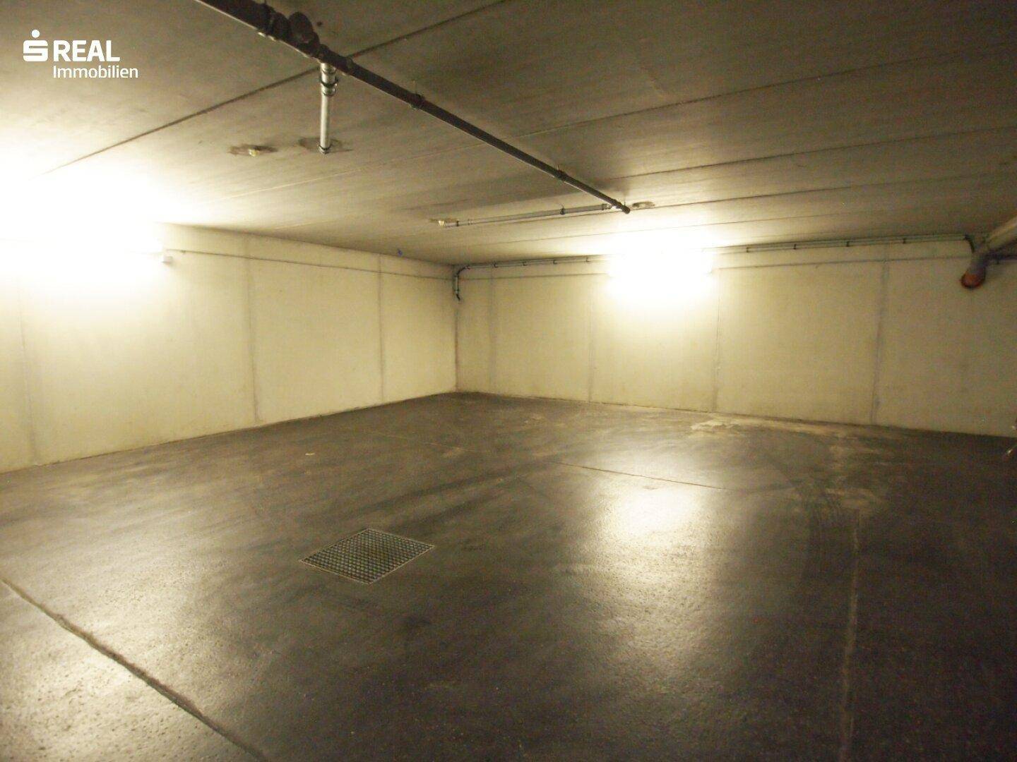 Geräumige Tiefgarage mit Betonboden und Beleuchtung, bietet Platz für mehrere Fahrzeuge.