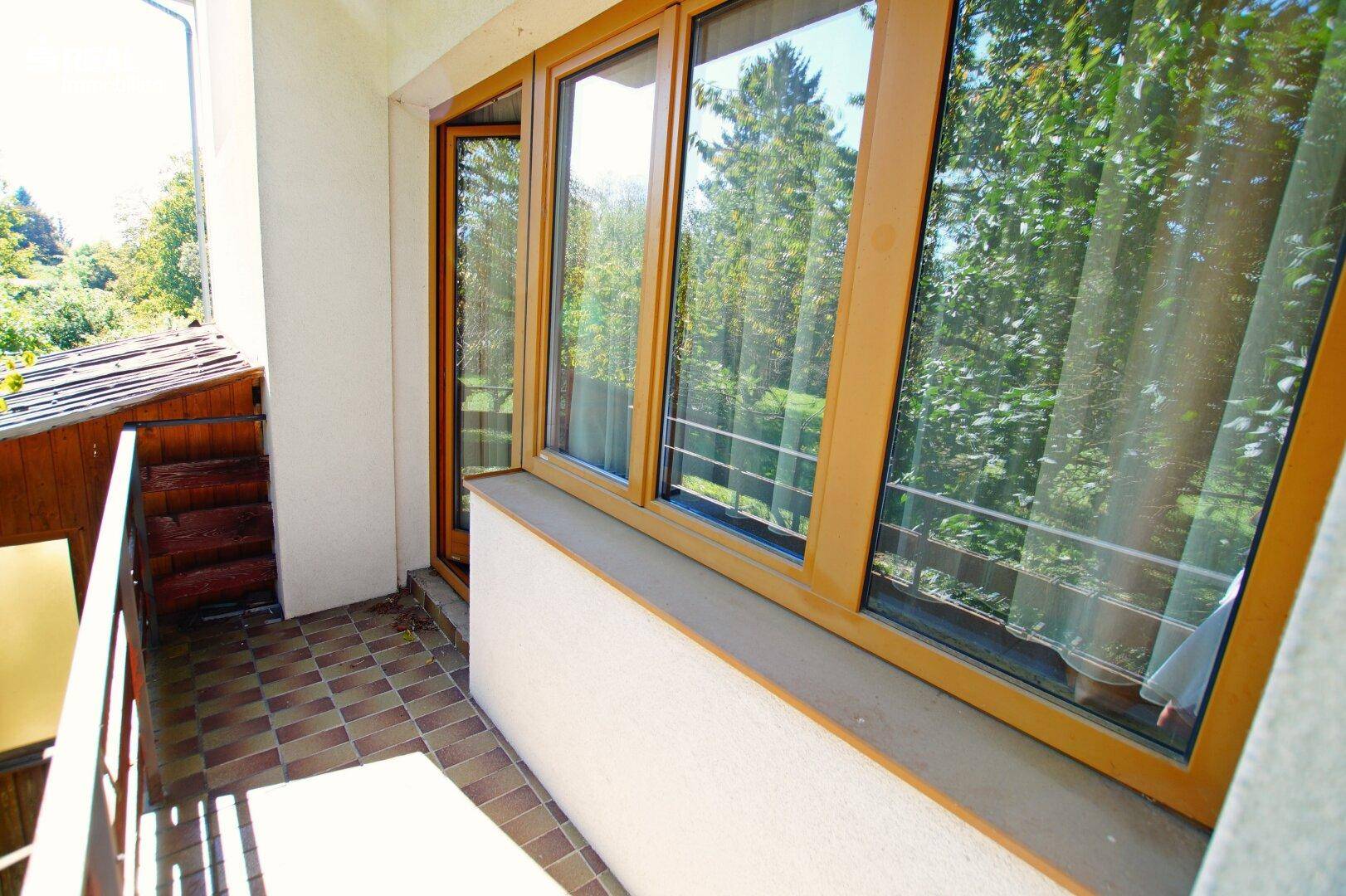 Gemütlicher Balkon mit Fliesenboden und einem schönen Blick ins Grüne.