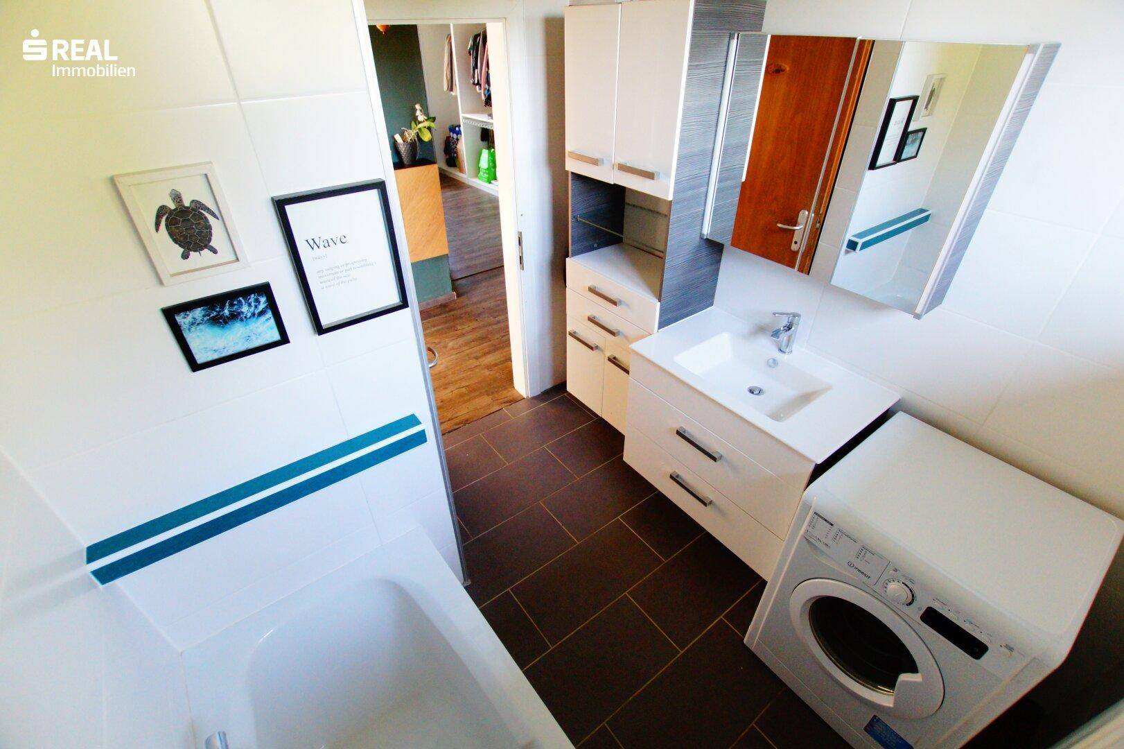 Badezimmer mit Waschbecken, Spiegelschrank und Waschmaschine, bietet praktische Funktionalität.