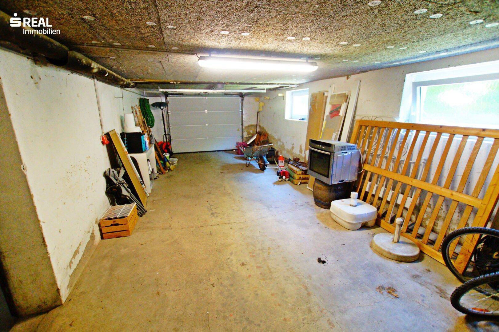 Geräumige Garage im Untergeschoss mit Garagentor und Fenstern, bietet viel Stauraum.