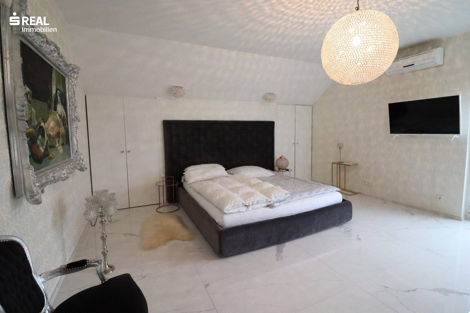 Geräumiges Schlafzimmer mit großem Bett, Klimaanlage und stilvoller Beleuchtung.