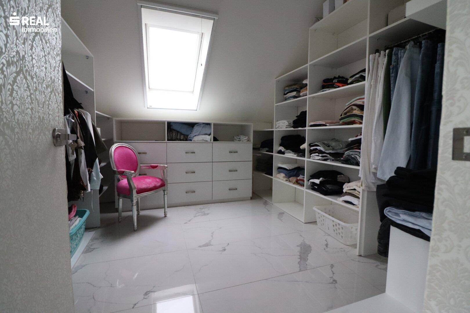 Geräumiger begehbarer Kleiderschrank mit Dachfenster und viel Stauraum.