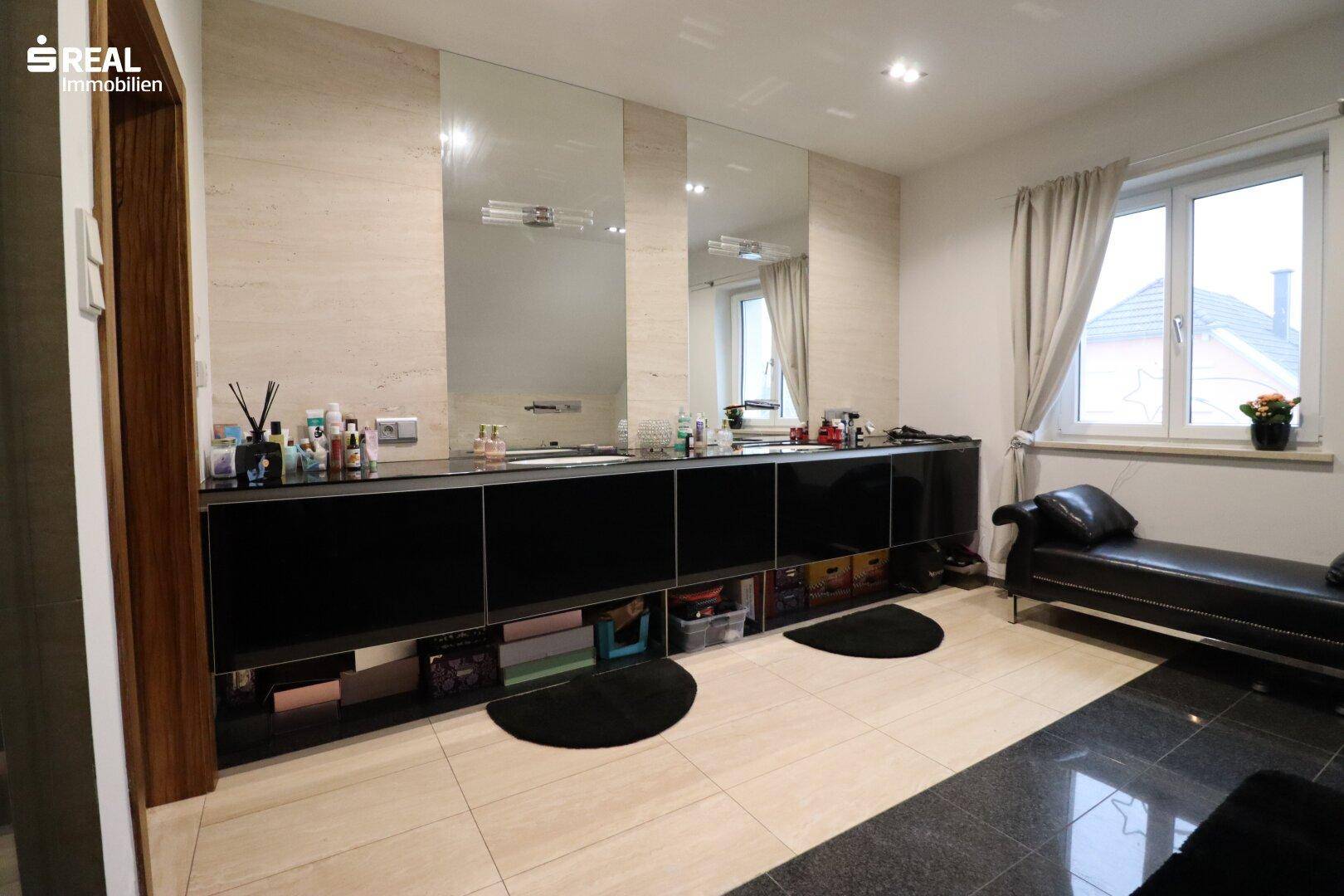 Modernes Badezimmer mit Doppelwaschbecken, großen Spiegeln und Fenster.