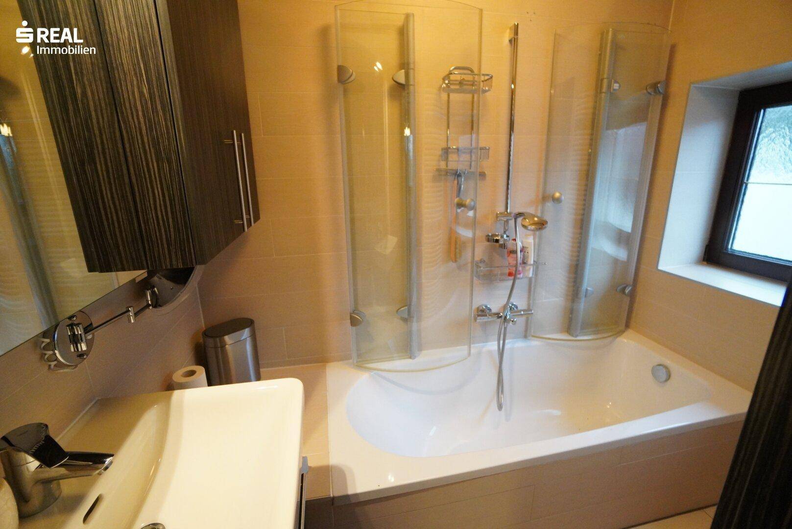 Modernes Badezimmer mit Badewanne, Duschabtrennung und Fenster.
