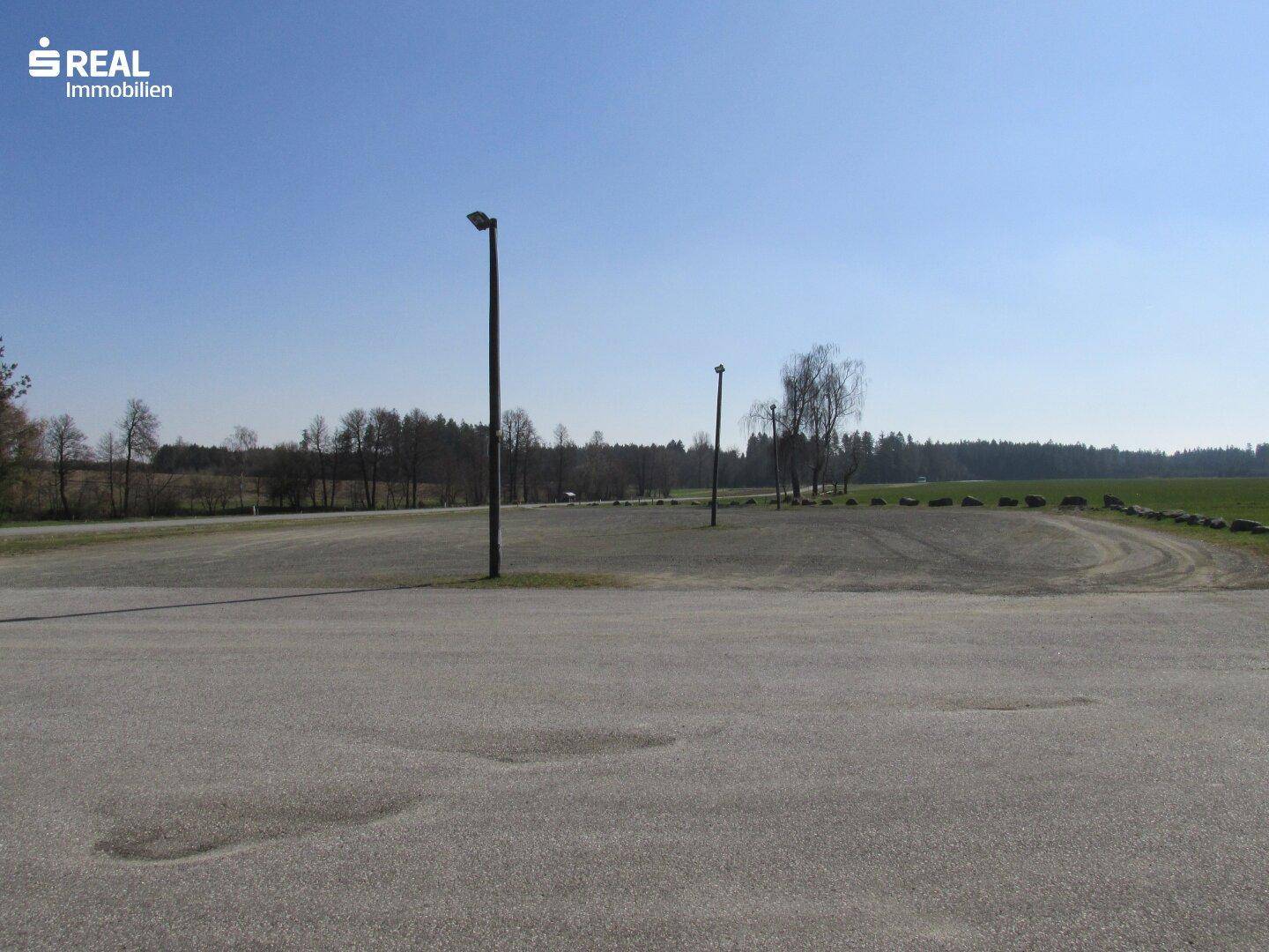 Großer asphaltierter Parkplatz mit Laternen und Blick auf die umliegende Landschaft.