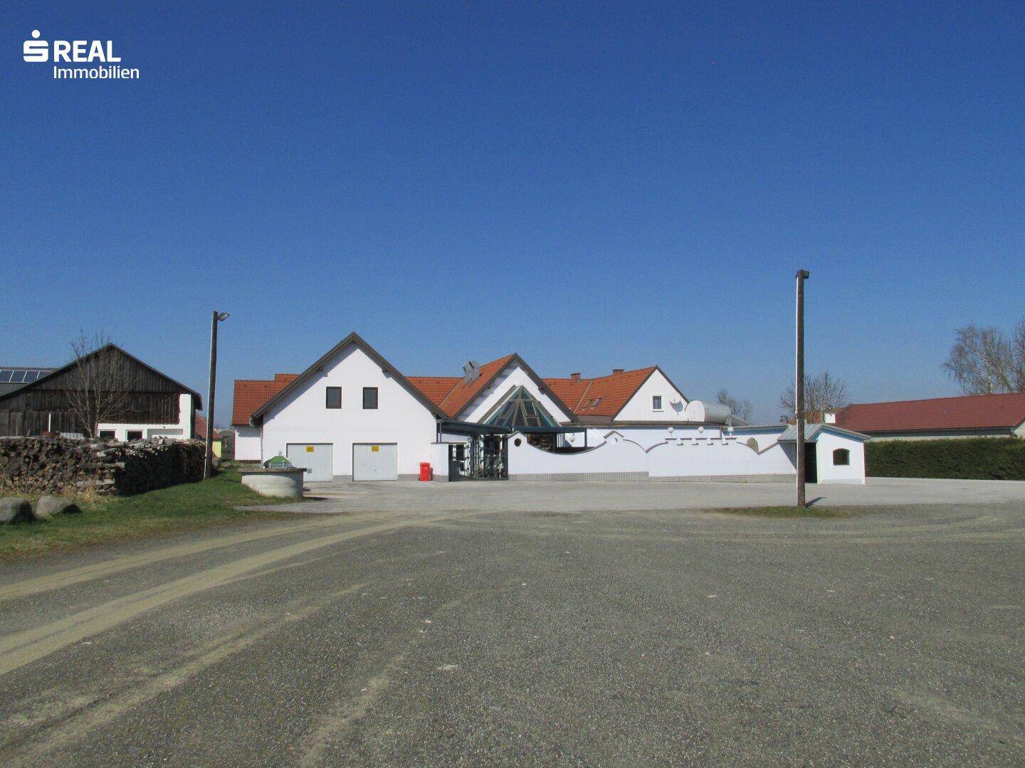 Weitläufige Außenansicht des Gebäudekomplexes mit Parkplatz und klarem Himmel.