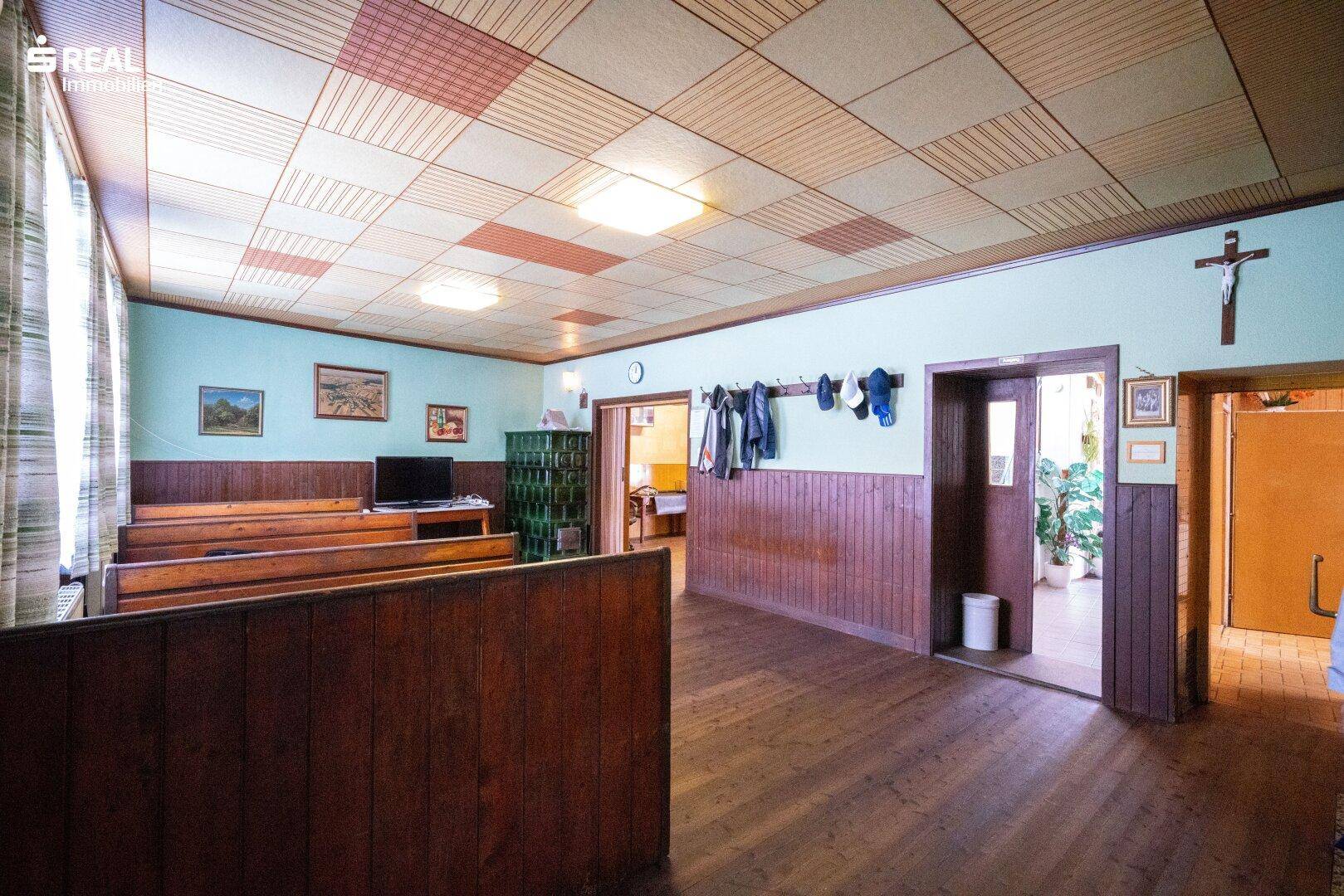 Geräumiger Essbereich mit Holzbänken, Holzboden und einem traditionellen Kachelofen.