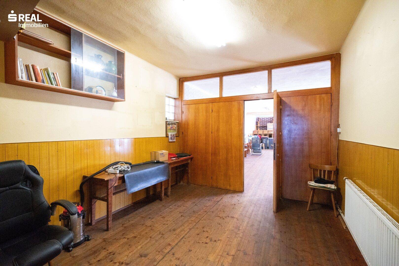Raum mit Holzvertäfelung, Holzboden und einem Regal mit Büchern.