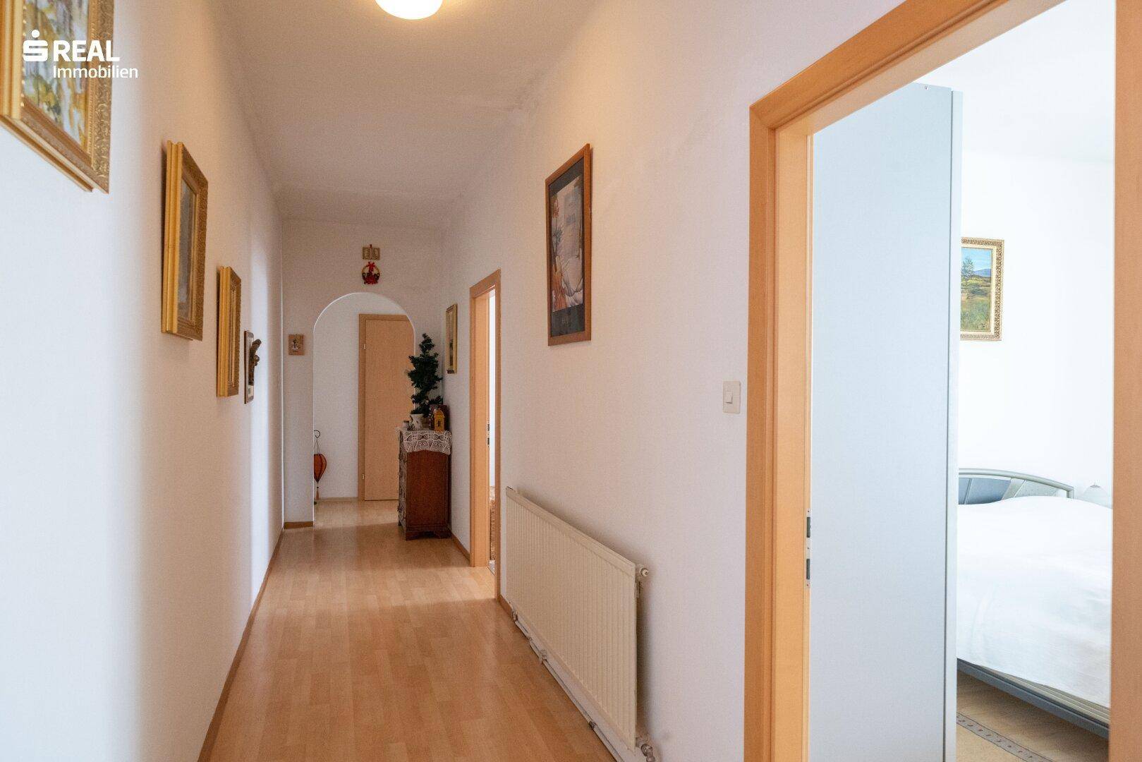 Heller Flur mit Laminatboden, Heizkörper und Zugang zu weiteren Räumen.