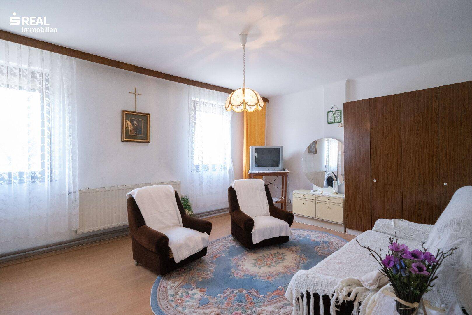 Schlafzimmer mit Holzboden, zwei Sesseln und einem großen Kleiderschrank.