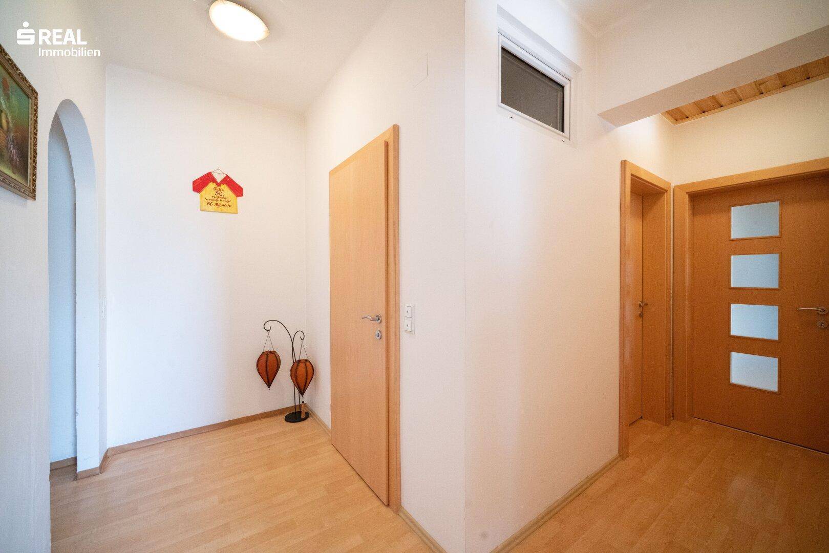 Heller Flur mit Holzfußboden und mehreren Türen, die zu verschiedenen Räumen führen.
