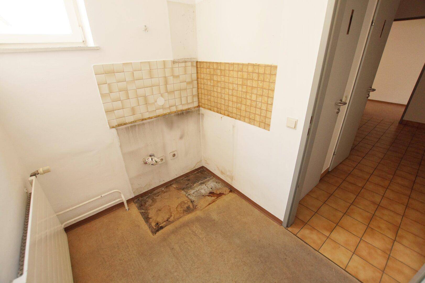 Kleiner Raum mit Fliesenrückwand, Heizkörper und Anschlüssen für eine Teeküche.