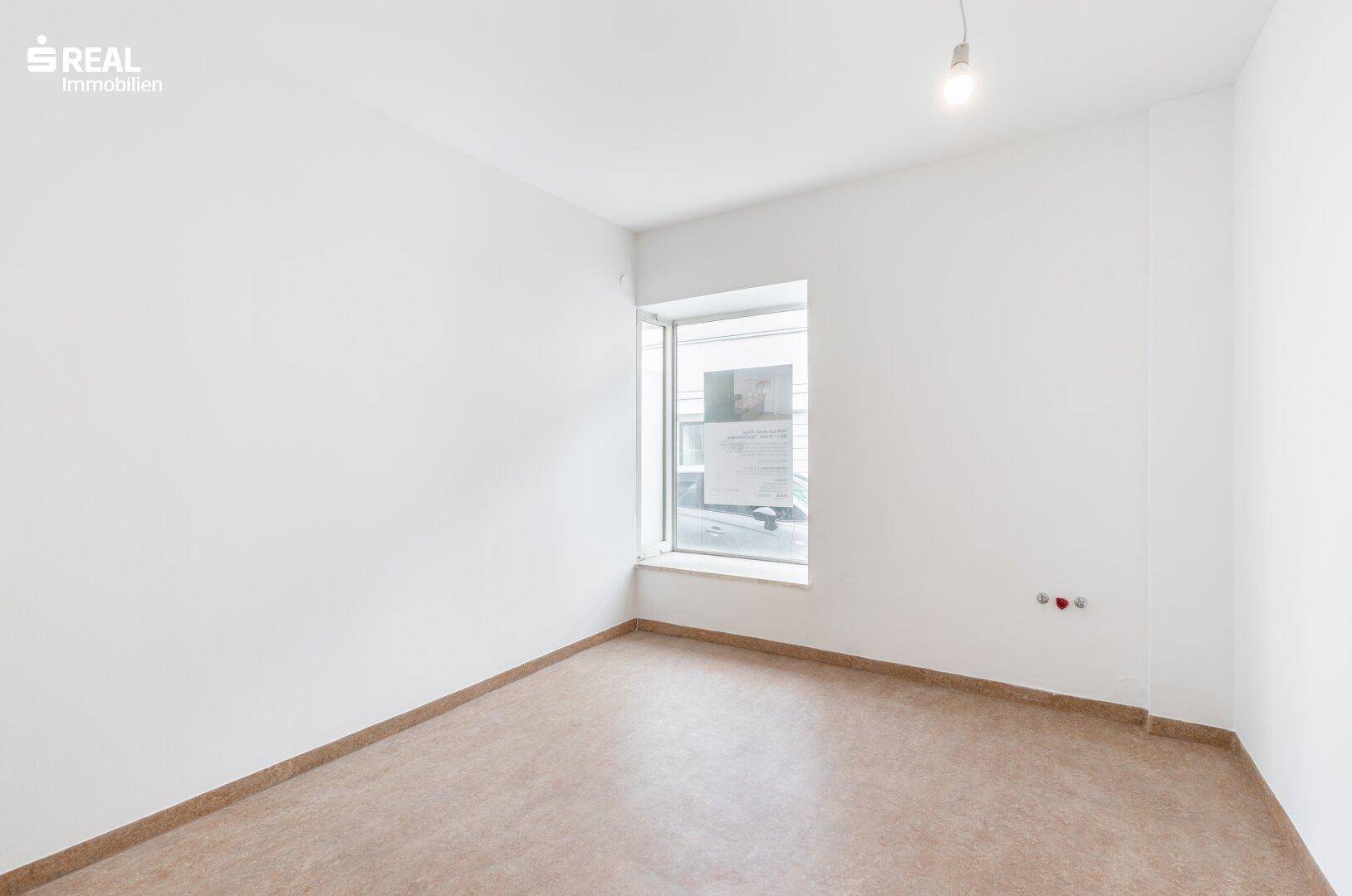 Kleiner, heller Raum mit einem Fenster und einfacher Beleuchtung, geeignet als Einzelbüro.