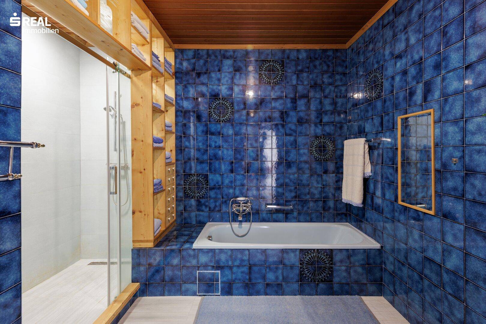Badezimmer mit blauen Fliesen, Badewanne und einer separaten Duschkabine.