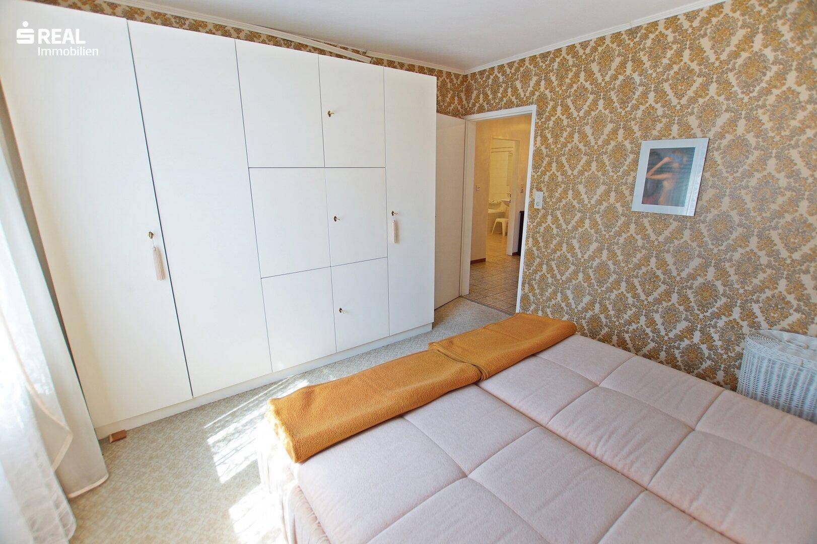 Schlafzimmer mit geräumigem Kleiderschrank und Zugang zum angrenzenden Flur.