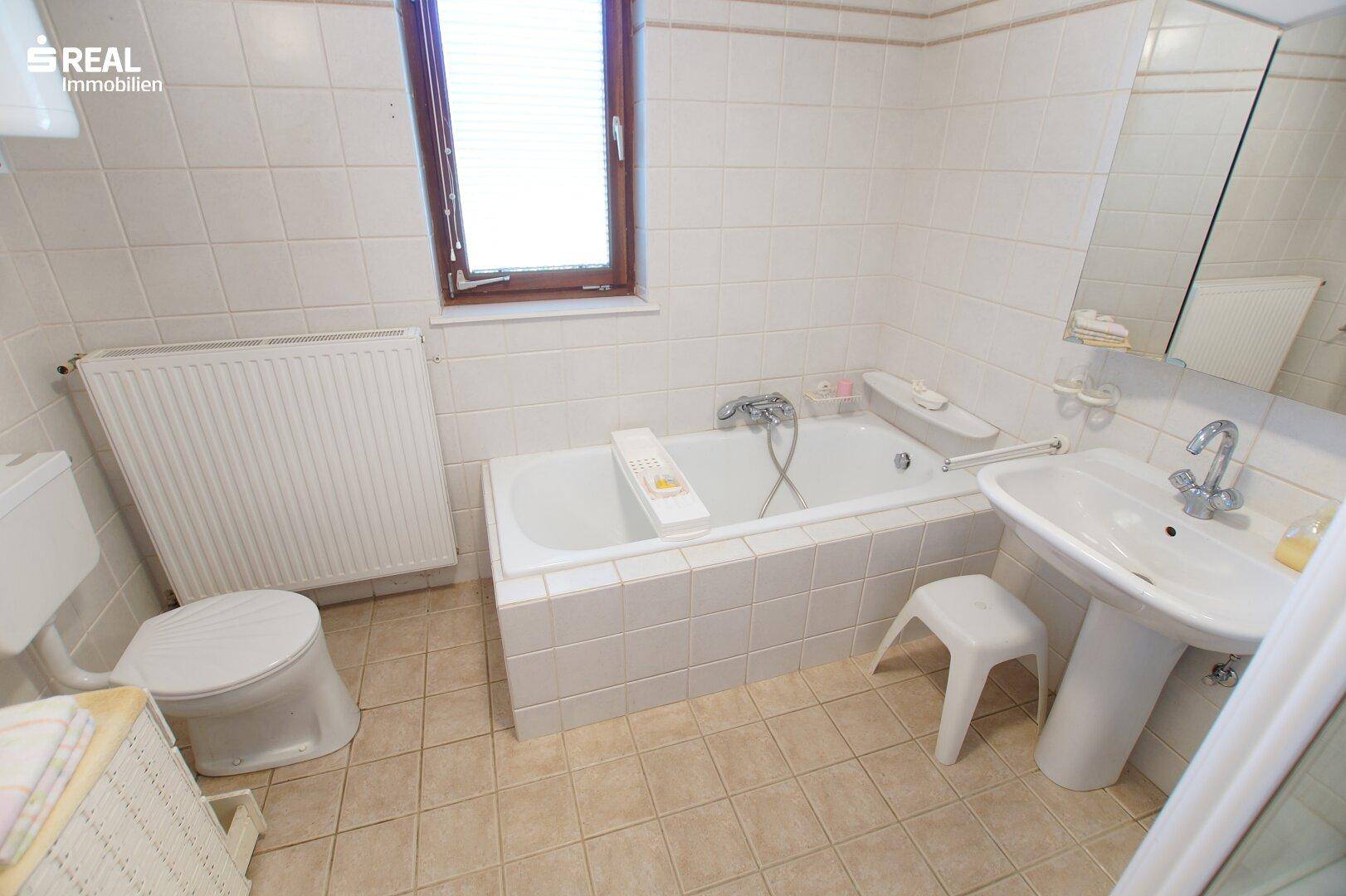 Gefliestes Badezimmer mit Badewanne, WC und Waschtisch, gut gepflegt.