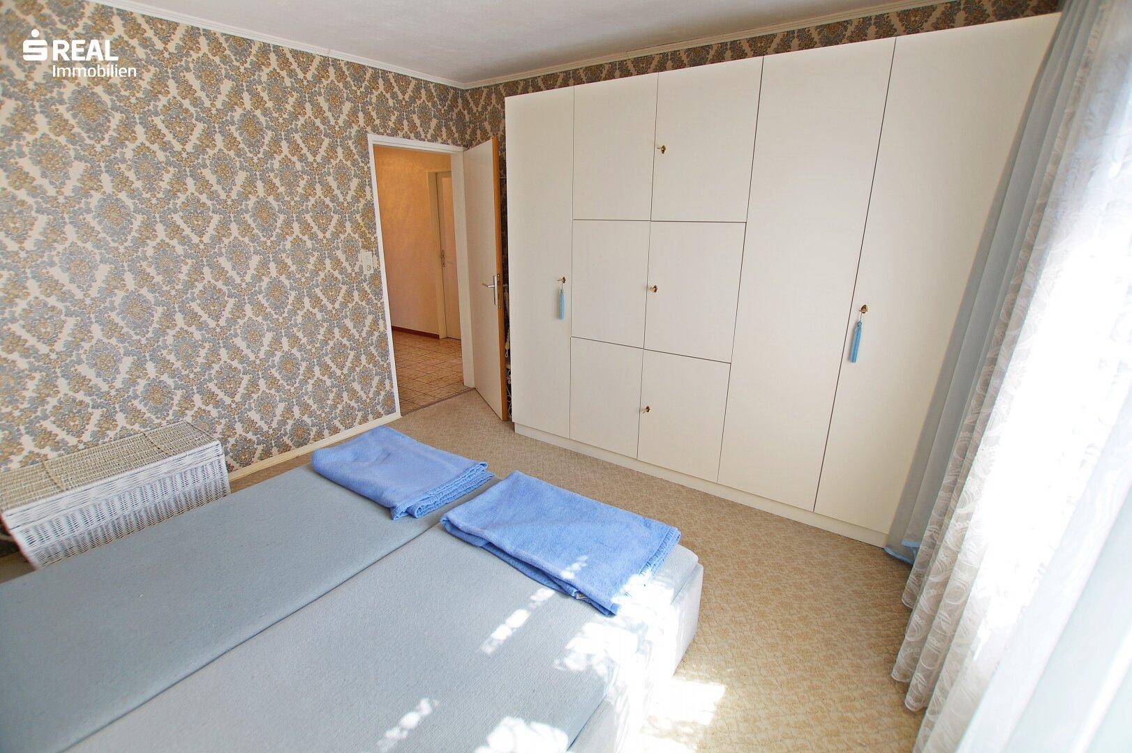 Zweites Schlafzimmer mit Einbauschrank und hellem Fenster, gut beleuchtet.