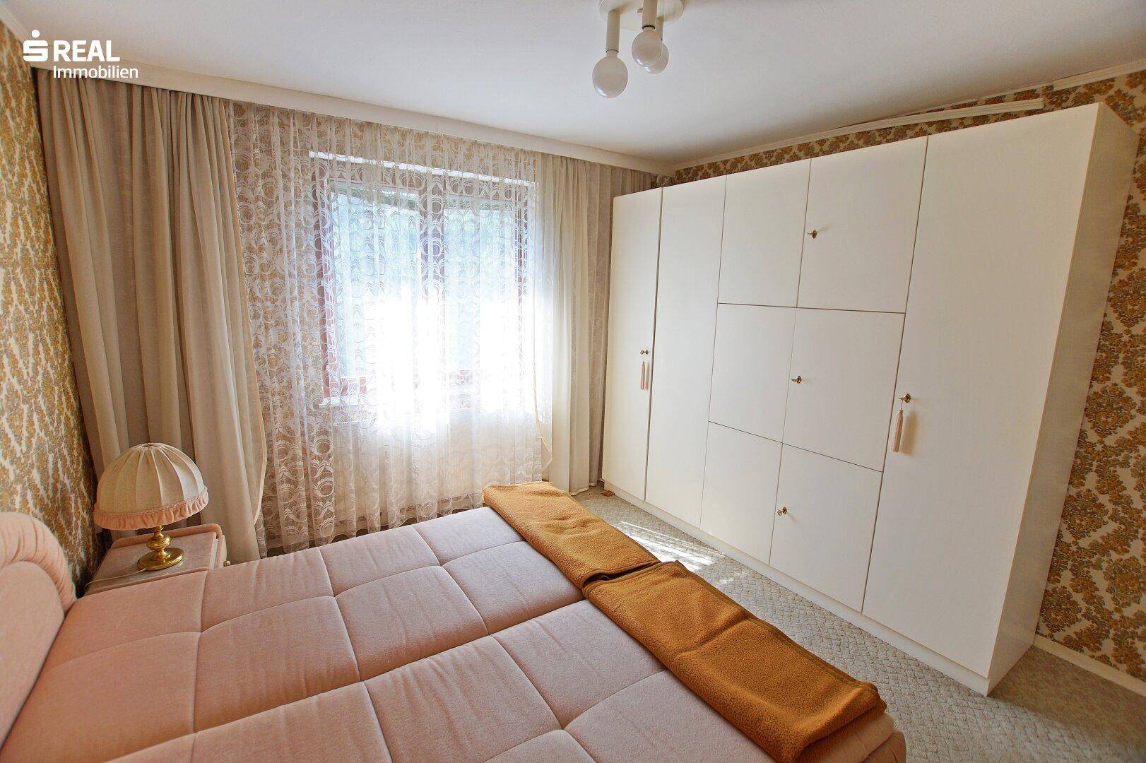 Schlafzimmer mit großem weißen Einbauschrank und hellem Fenster.