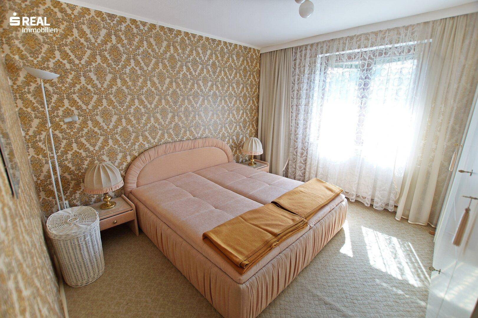 Gemütliches Schlafzimmer mit gemusterter Tapete, Teppichboden und Doppelbett.