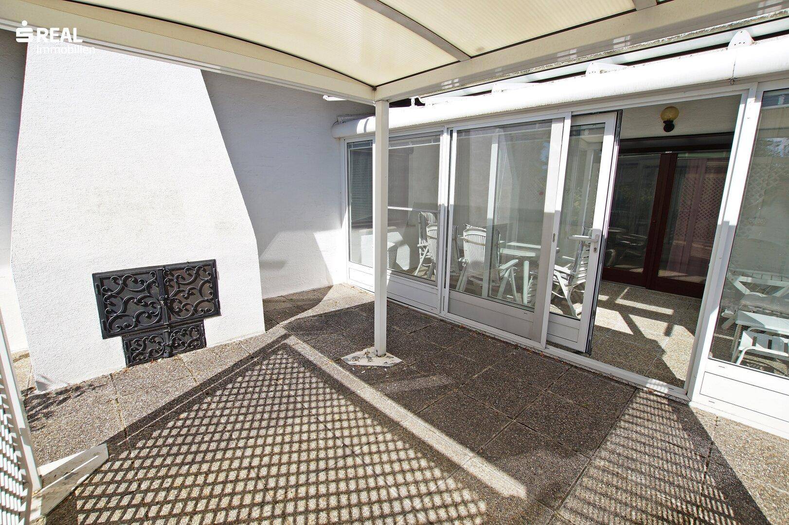 Überdachte Terrasse mit Außenkamin und Fliesenboden, ideal für gesellige Abende.