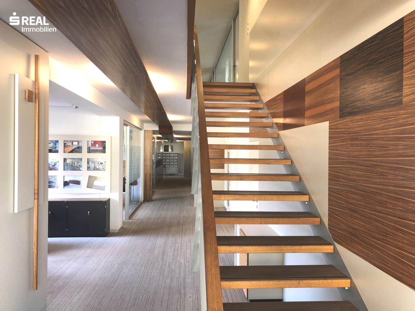 Moderne Holztreppe mit Glasgeländer und dekorativen Holzelementen an den Wänden.