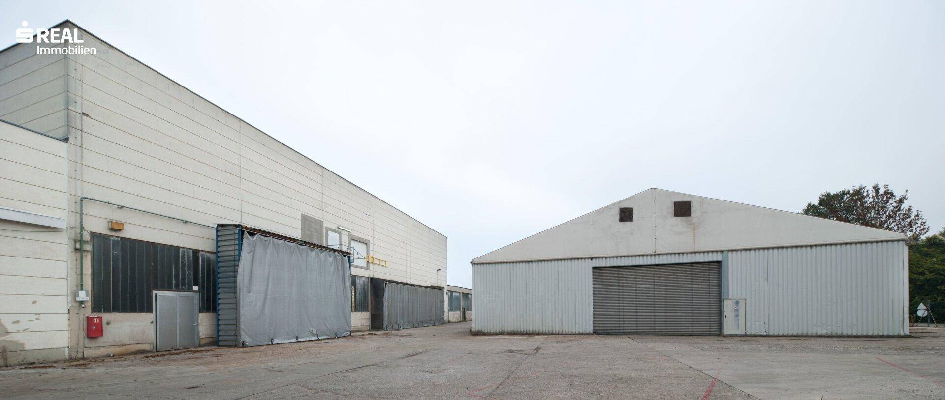 Außenansicht von zwei großen Industriehallen mit Metallfassaden und einem weitläufigen Vorplatz.