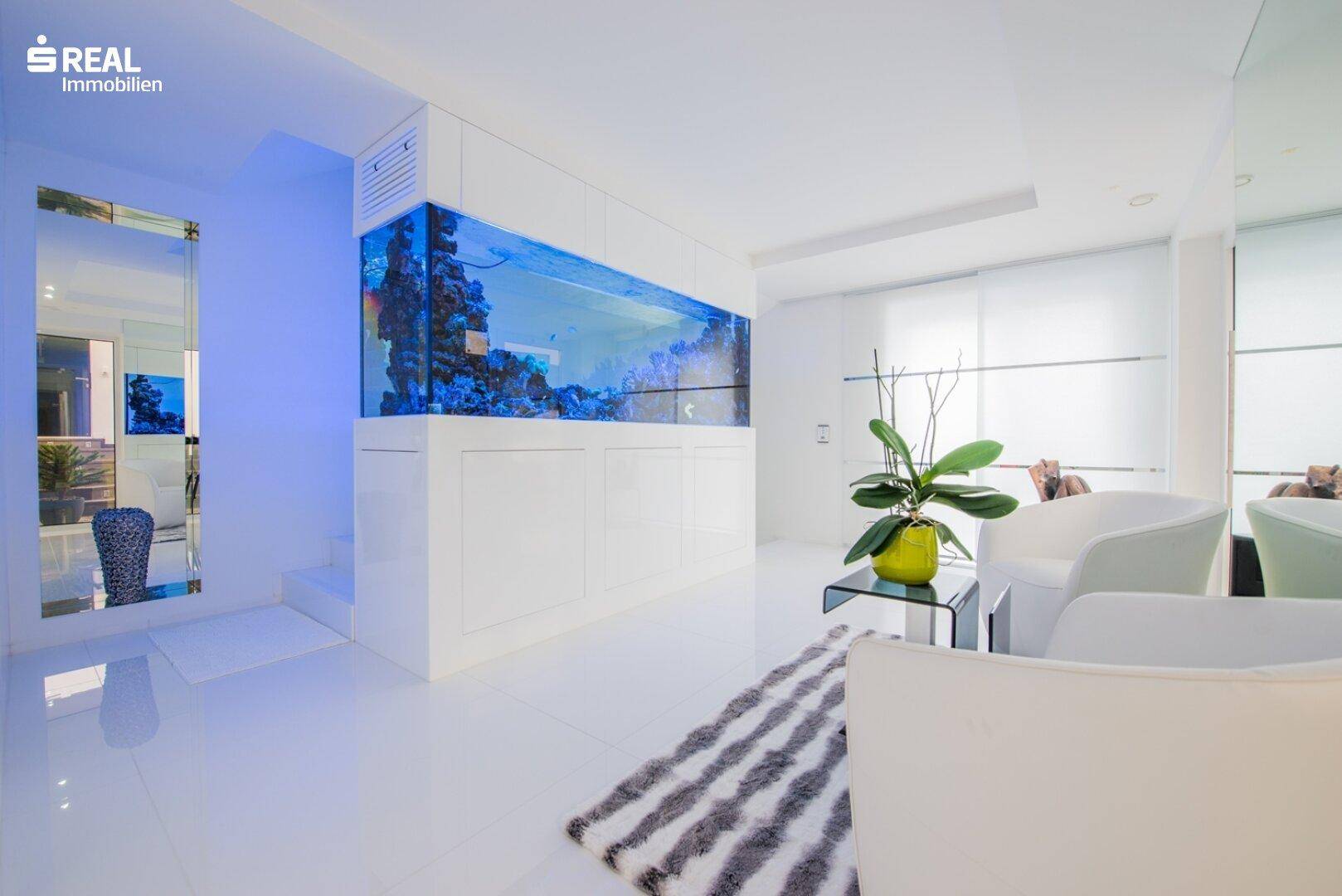 Heller, moderner Wohnbereich mit großem Aquarium und weißen Fliesenboden.