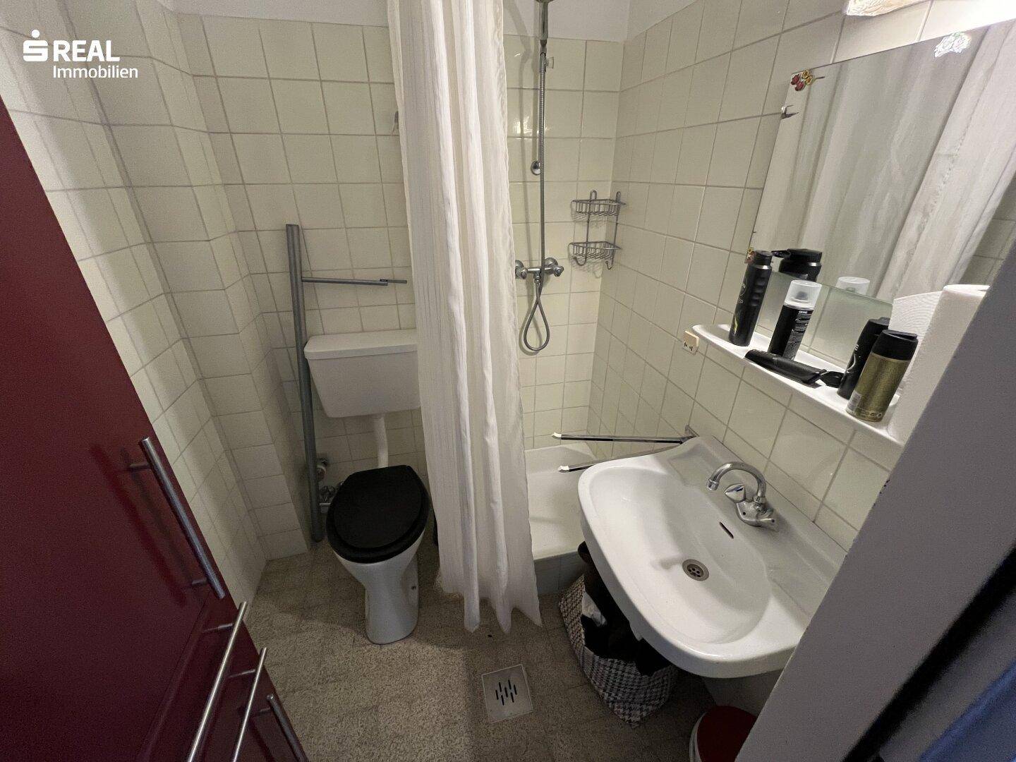 Funktionales Badezimmer mit Dusche, WC und Waschbecken, ausgestattet mit hellen Fliesen.