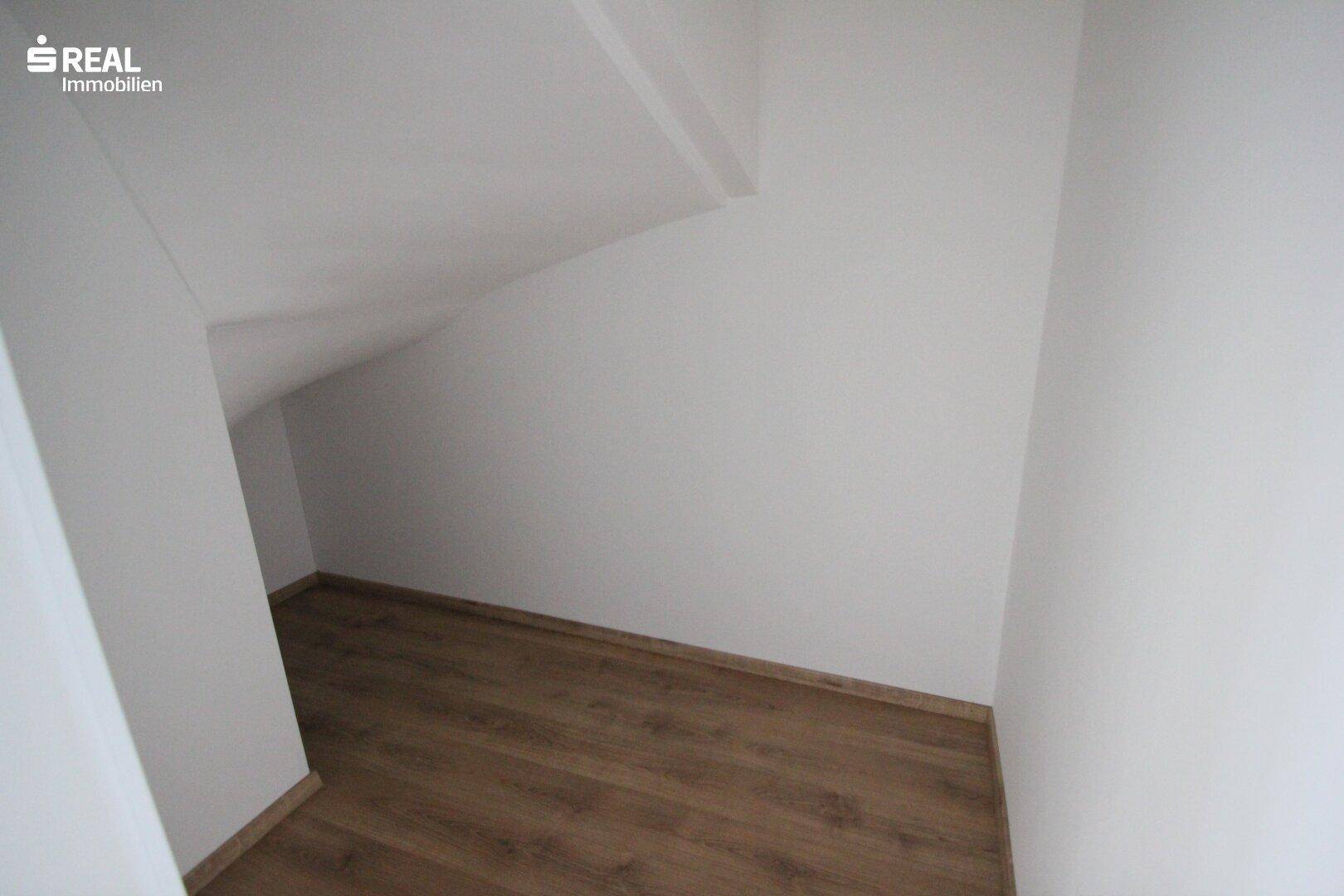 Praktischer Abstellraum mit Laminatboden und schräger Decke, ideal für zusätzlichen Stauraum.