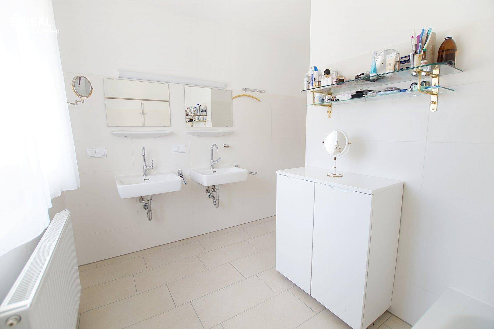 Modernes Badezimmer mit zwei Waschbecken, Spiegelschränken und Fliesenboden.