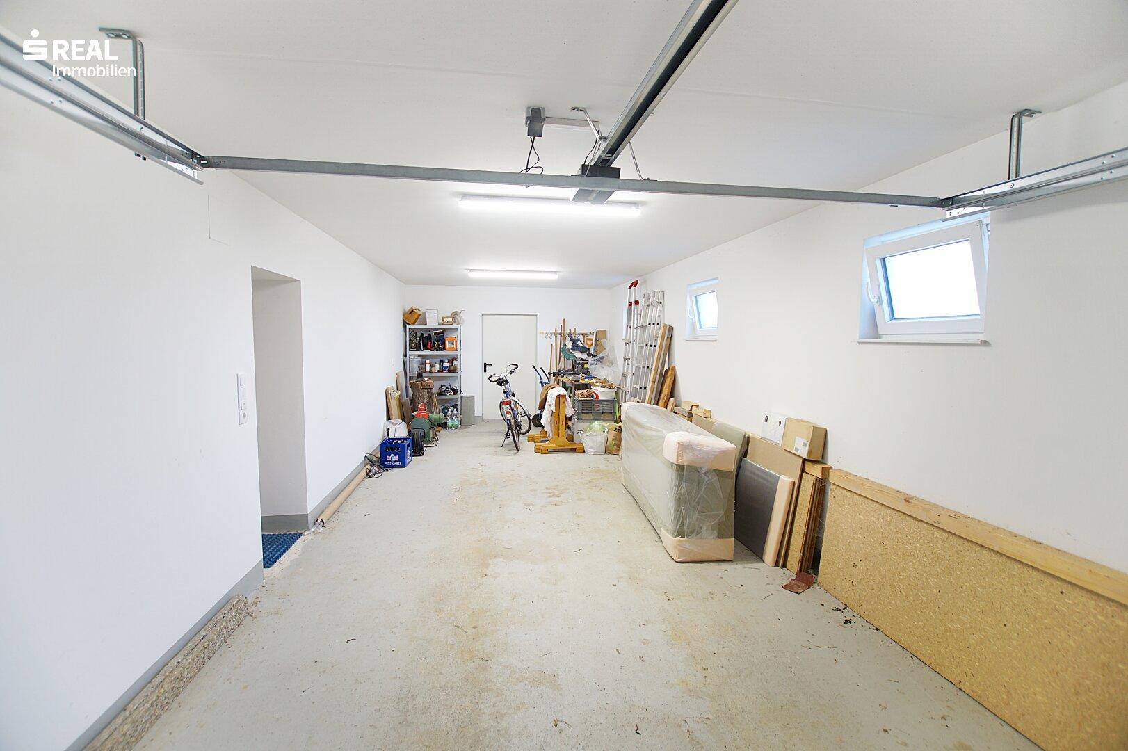 Geräumige Garage mit Betonboden, Fenstern und Stauraum.