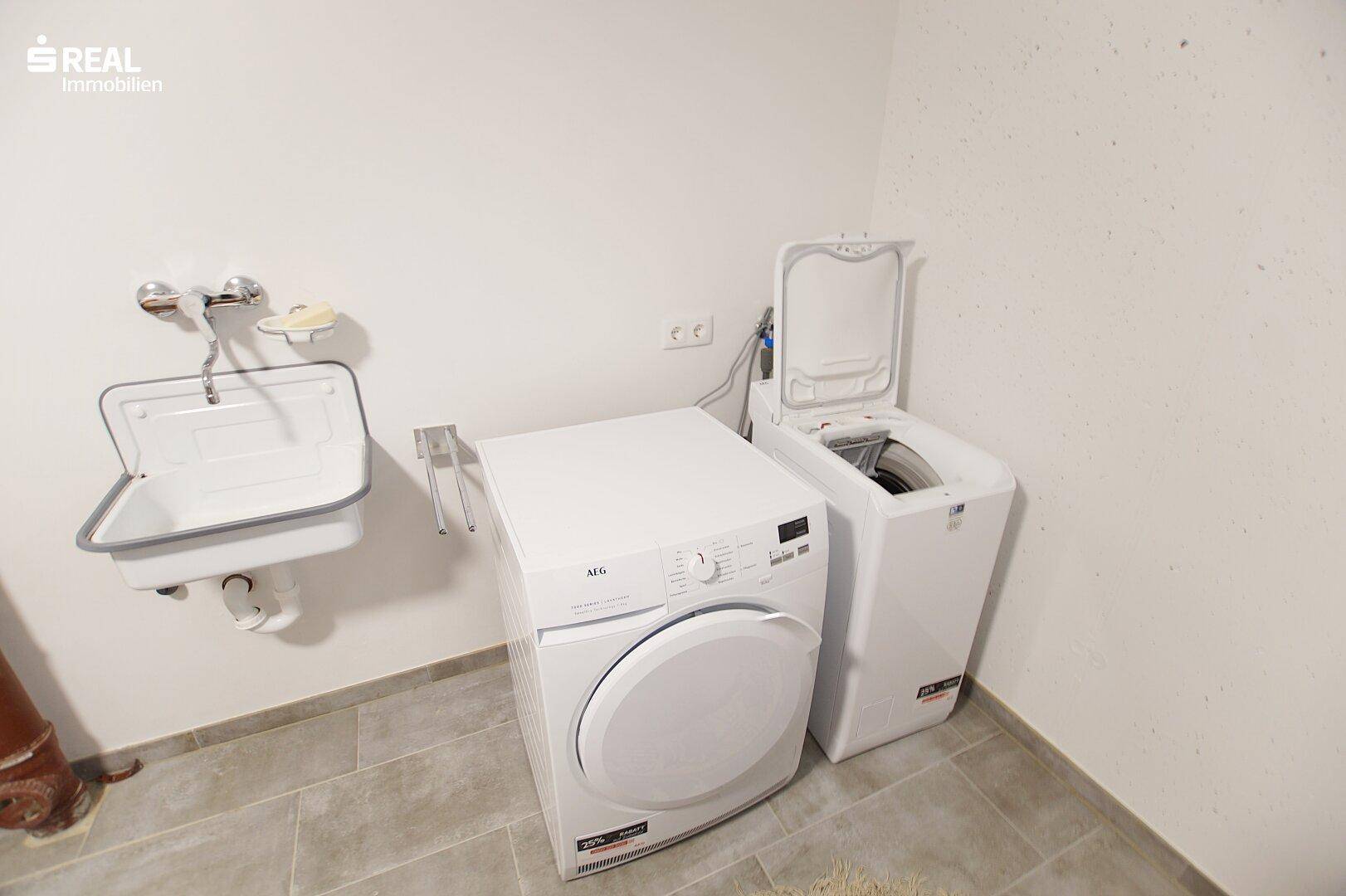 Waschküche mit Waschmaschine, Trockner und Waschbecken.