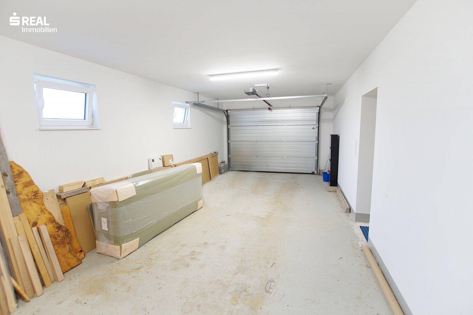 Große Garage mit Rolltor, Betonboden und viel Platz.