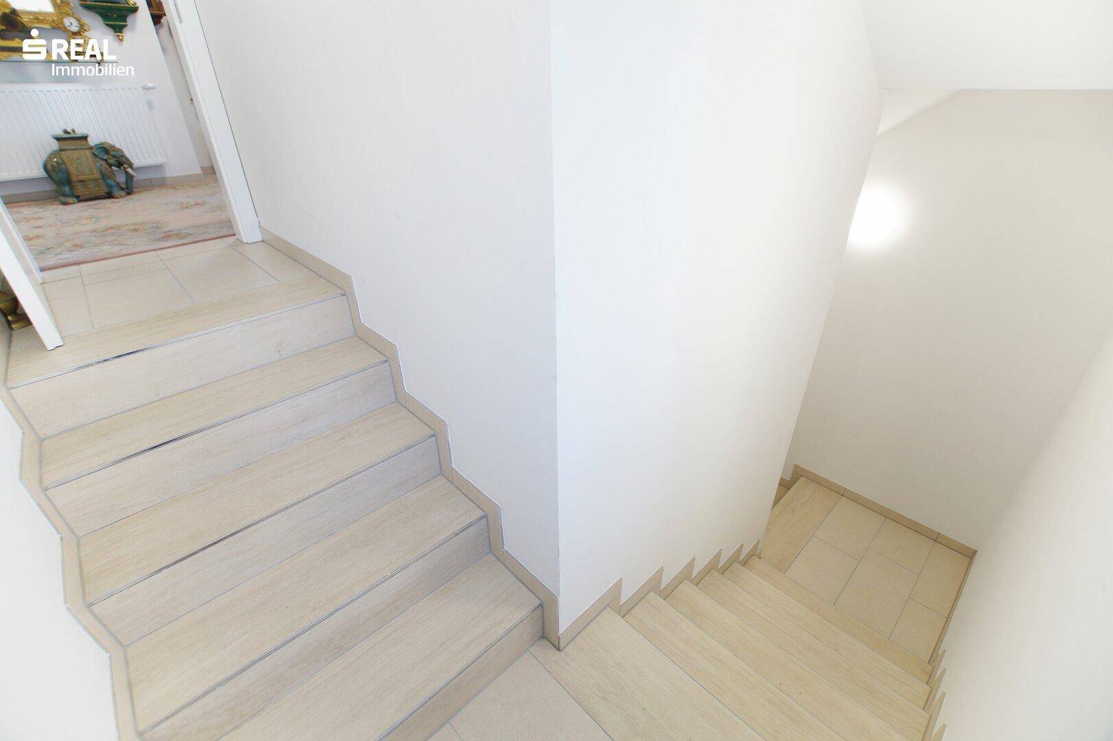 Treppenhaus mit Fliesenboden, das verschiedene Ebenen des Hauses verbindet.