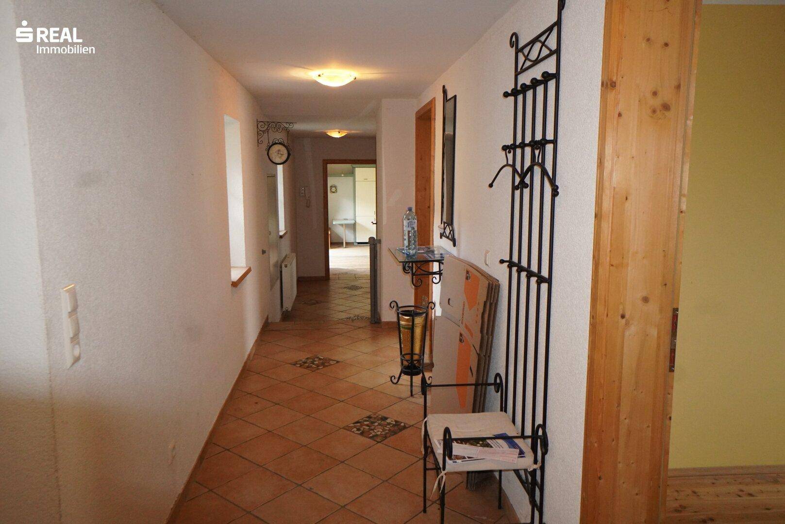 Heller Flur mit Terrakotta-Fliesenboden und traditioneller Garderobe.