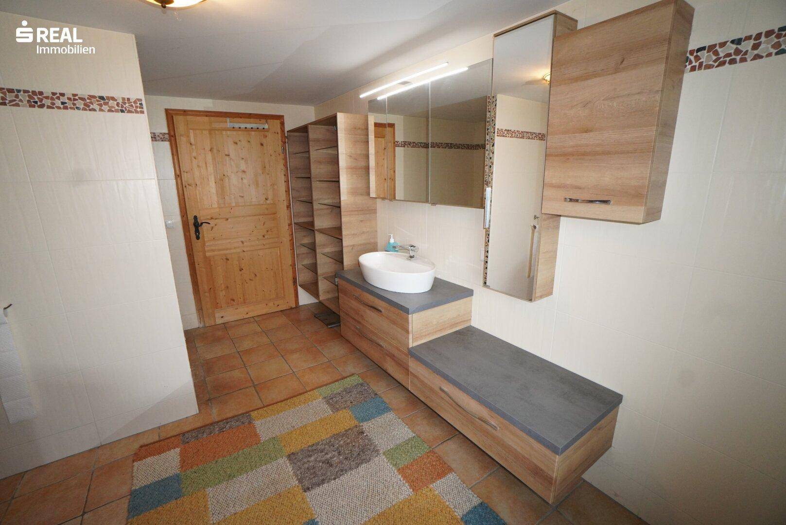 Badezimmer mit modernem Waschtisch, Spiegelschrank und Terrakotta-Fliesenboden.