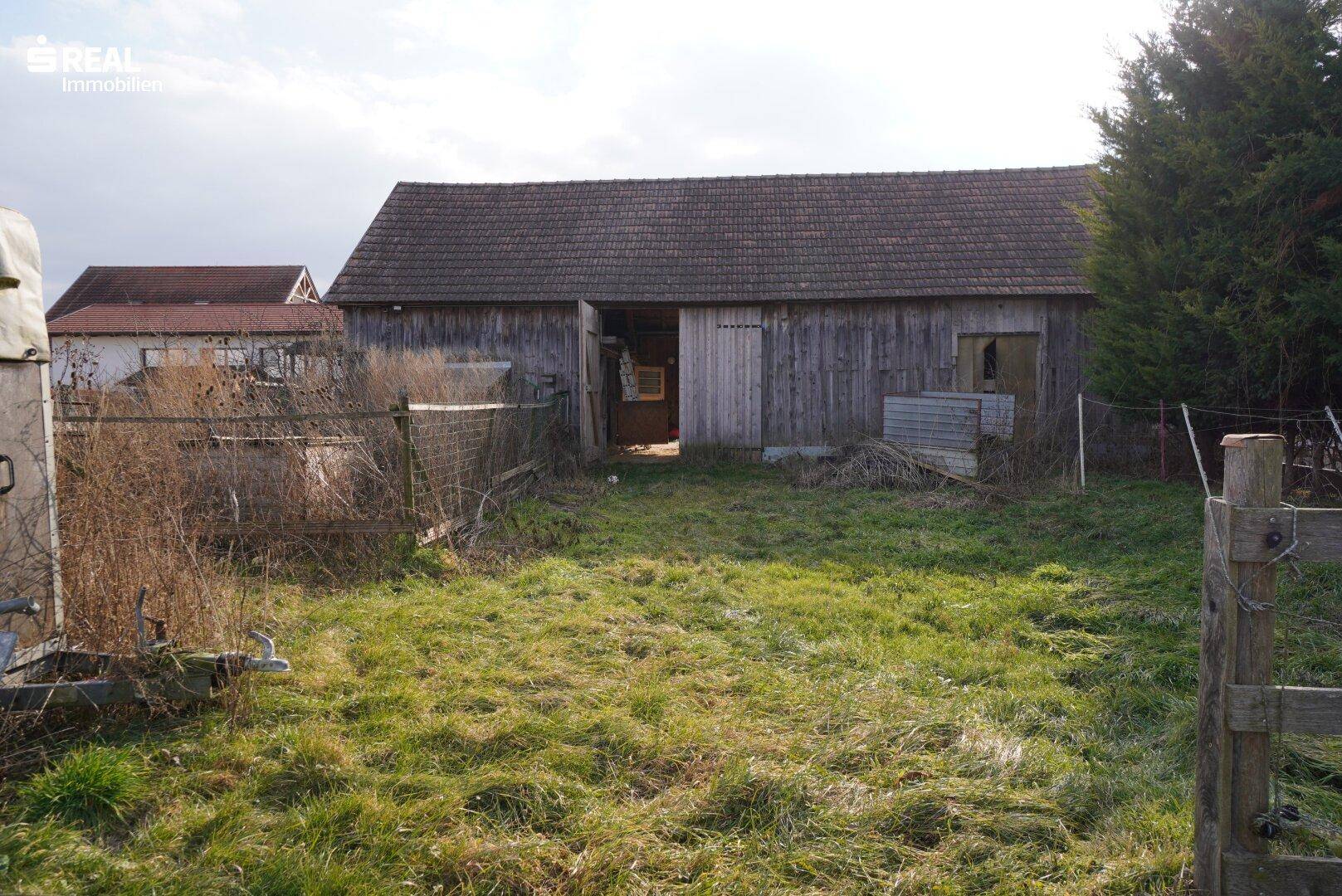 Gartenbereich mit Rasen und einem alten Holzschuppen im ländlichen Stil.