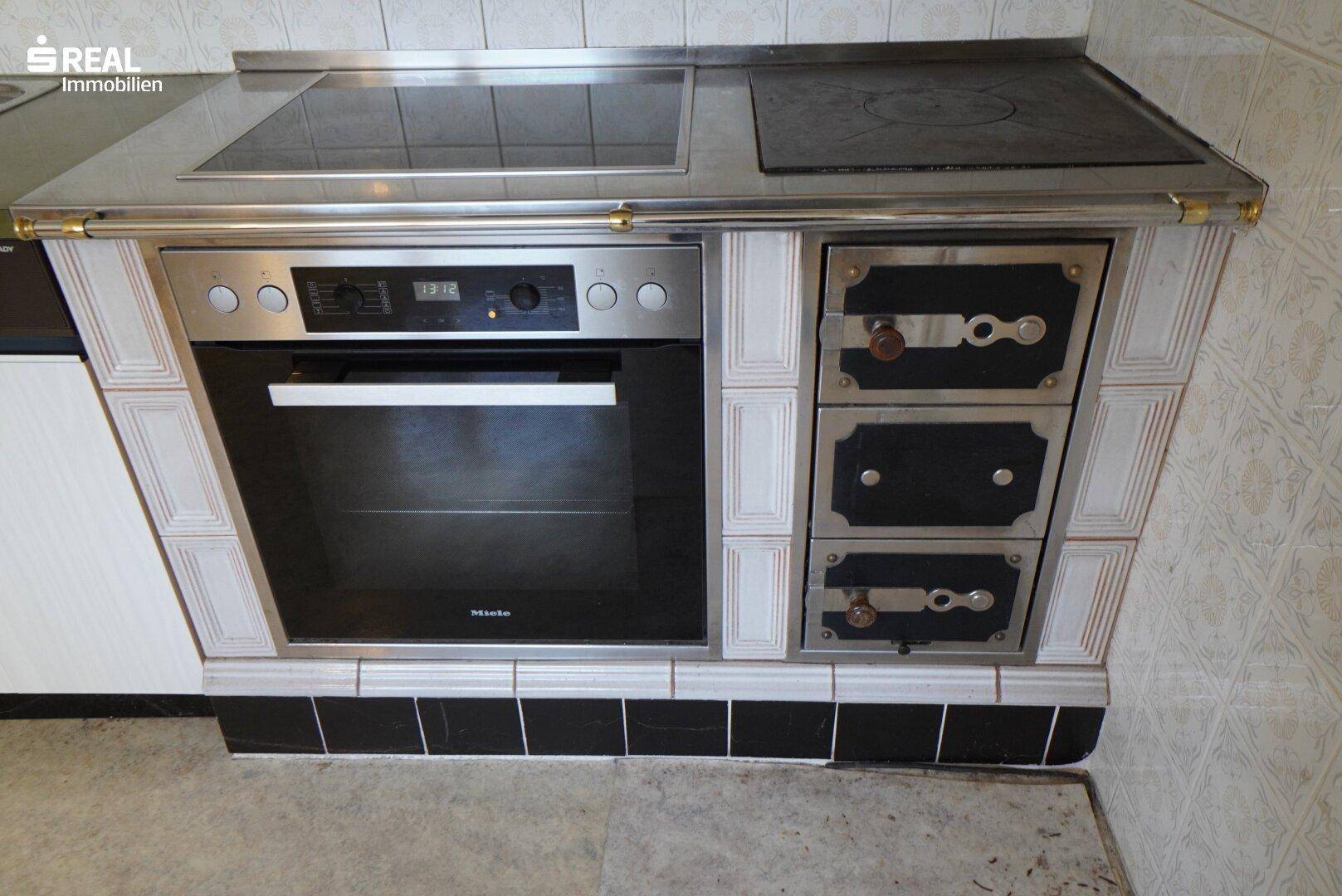 Detailansicht eines traditionellen Kachelofens mit integriertem Miele-Backofen und Kochfeldern.