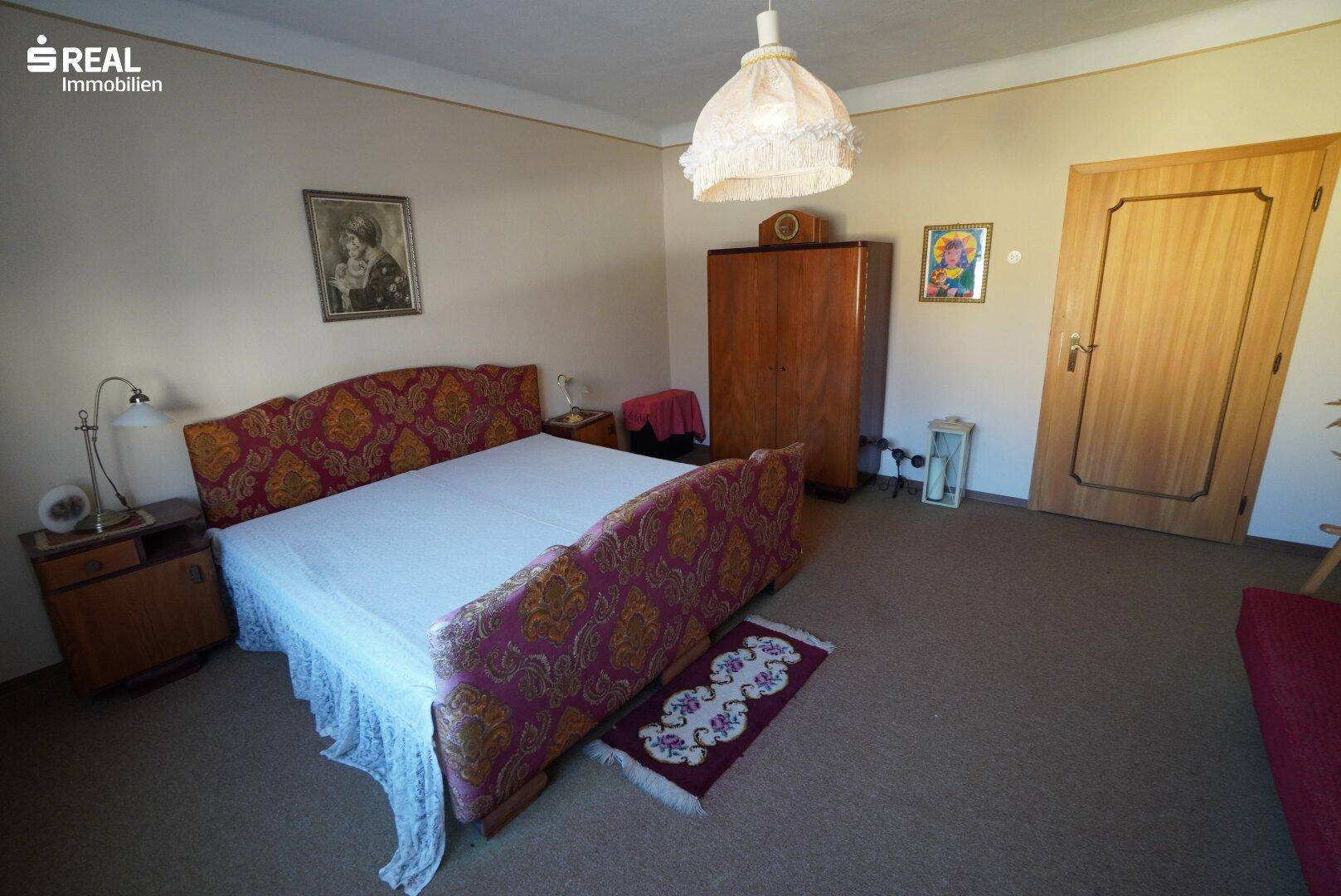Geräumiges Schlafzimmer mit Doppelbett, Holzschrank und Teppichboden.