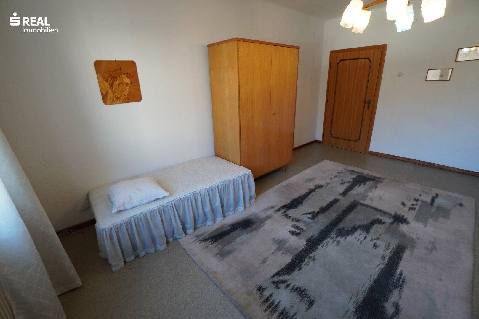 Schlafzimmer mit Teppichboden, einem Einzelbett und einem Kleiderschrank.