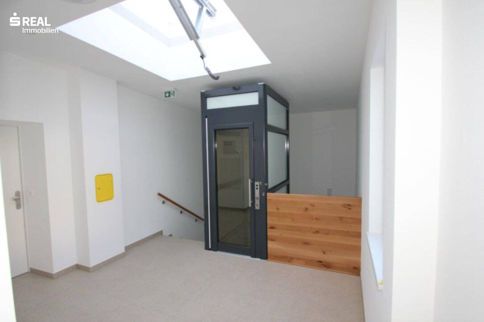 Moderner Eingangsbereich mit Aufzug und Treppenhaus, hell und funktional gestaltet.