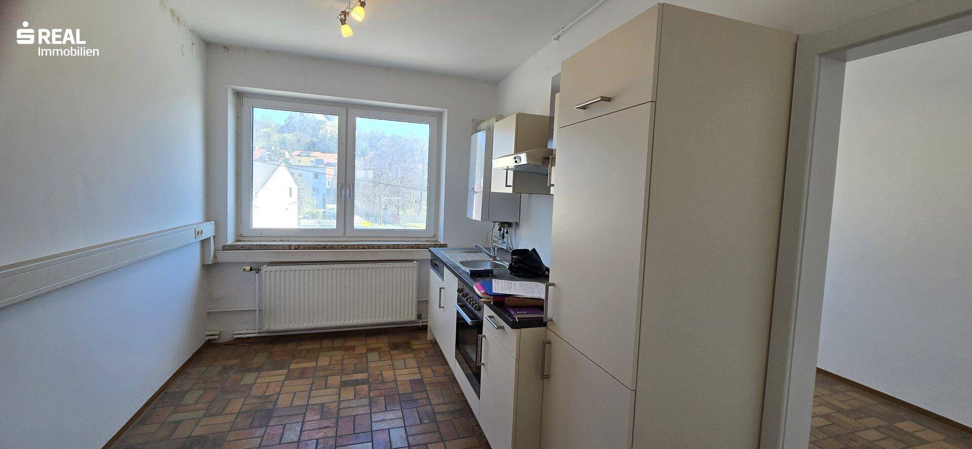 Funktionale Küche mit Einbauschränken, Spüle, Herd und einem Fenster für Tageslicht.
