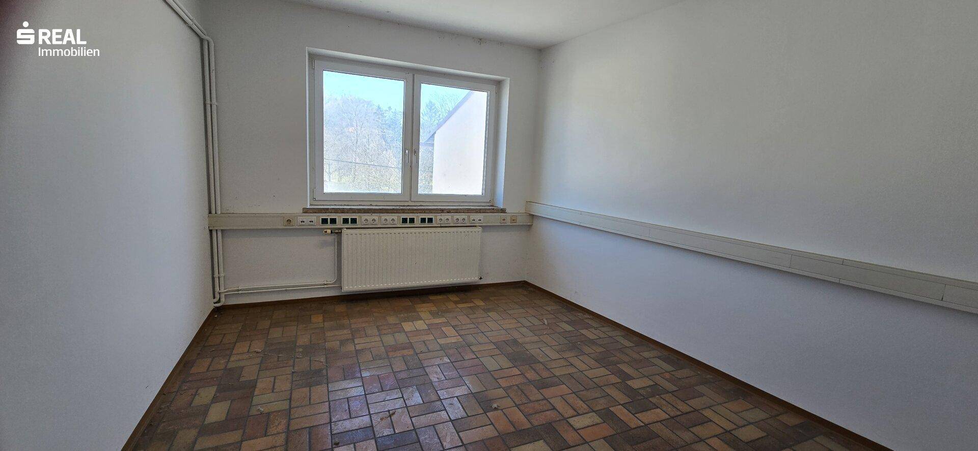 Kleines, helles Zimmer mit Parkettboden und einem großen Fenster, ideal als Büro oder Gästezimmer.