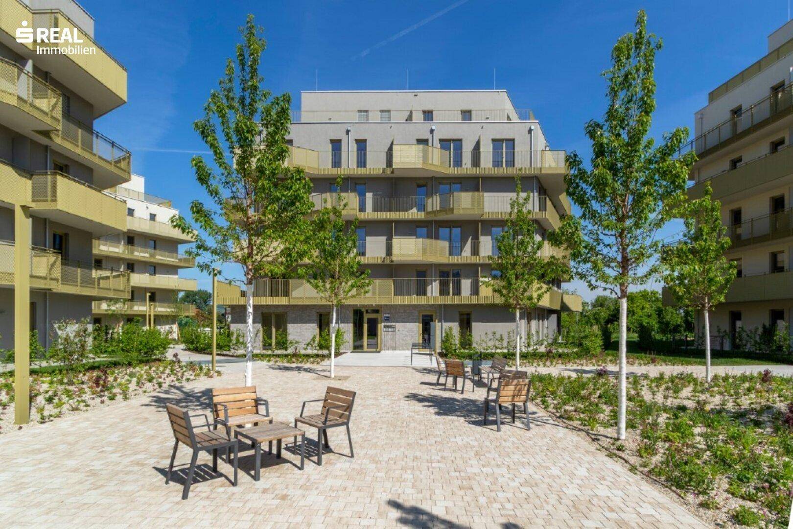 Zentraler Innenhof mit Sitzgelegenheiten und Bäumen, umgeben von modernen Wohngebäuden.