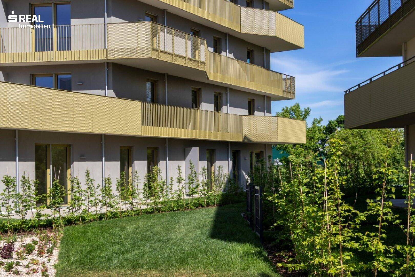 Erdgeschosswohnung mit direktem Zugang zu einem privaten Rasenbereich und junger Bepflanzung.